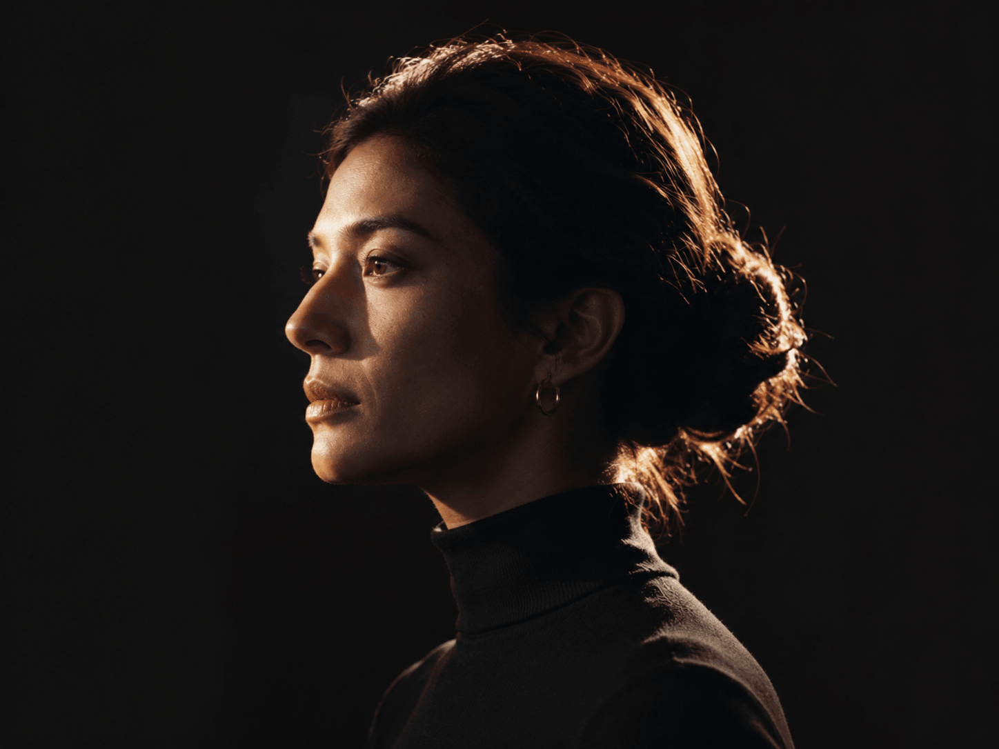 A professional in profile, rim-lit against black.
